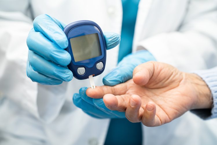 Doctor check diabetes from finger blood sugar level with finger lancet.