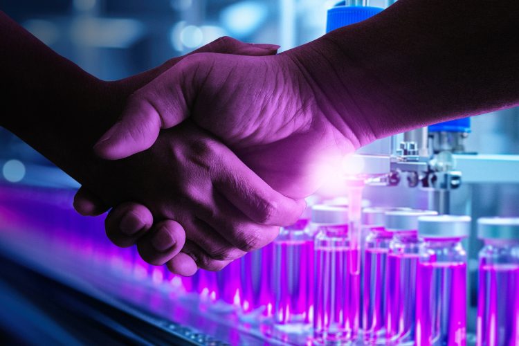 Two scientists shaking hands in a laboratory setting