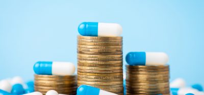 Stacks of coins between medical pills capsules.