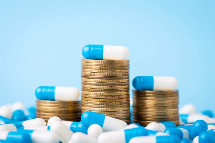 Stacks of coins between medical pills capsules.